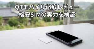 窓辺の白いテーブルに置かれた無地のSIMカードとスマートフォン、QTモバイルのイメージ